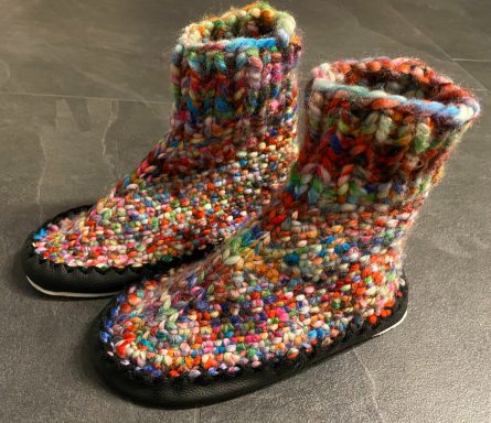 Bunte, gestrickte Hausschuhsocken mit schwarzer Sohle.