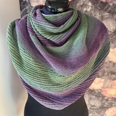 Lila-grüner, gestreifter Schal, elegant drapiert über einem Mannequin.