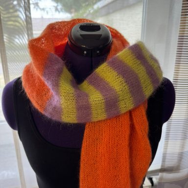 Bunte Strickschal in Orange, Lila und Gelb, drapiert um einen Aufnahme-Form.