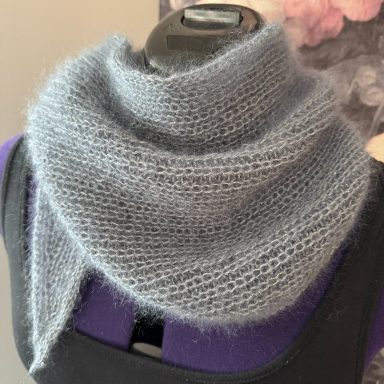 Graue, schlichte Strickschal, drapiert auf einer Mannequin-Schulter.