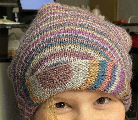 Bunt gestreifte Mütze mit geometrischem Muster auf einem Kopf.