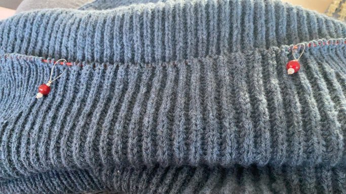 Dunkelblauer Pullover mit feinen Rippen und roten dekorativen Elementen.