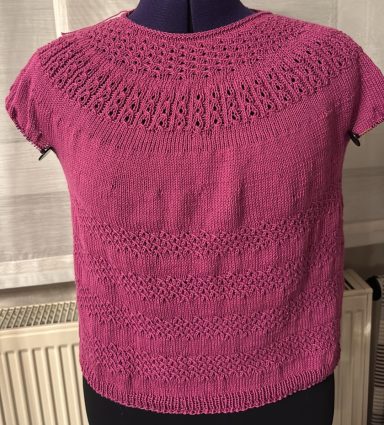 Rosa gestricktes Oberteil mit Rundhalsausschnitt und Lochmuster.