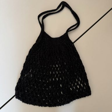 Schwarze Netztragetasche mit langen Henkeln.