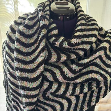 Schwarz-weißer Schal mit wellenförmigem Muster, lässig drapiert.