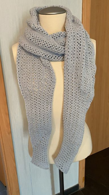 Grau gestrickter Schal auf einem Mannequin im Innenraum.